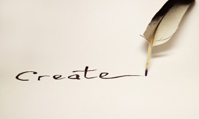 Inscription " Create " written with a feather on a white paper