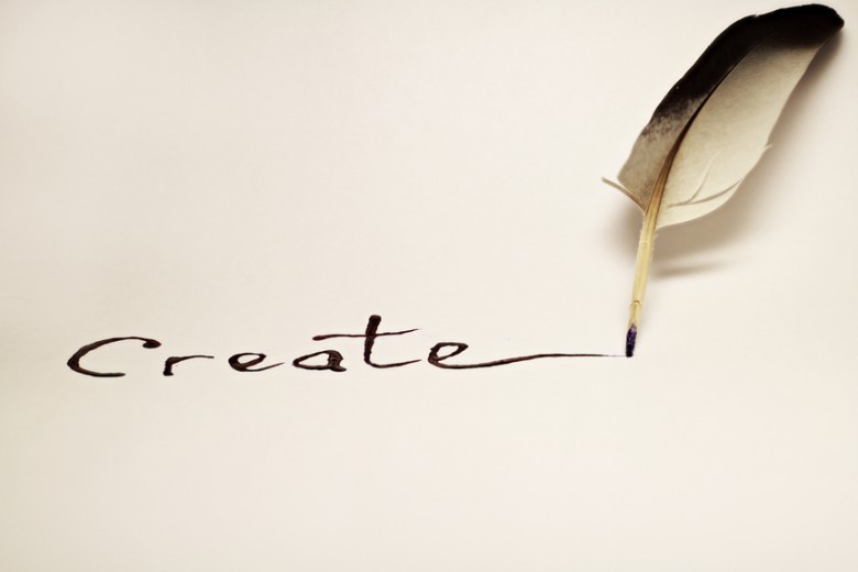 Inscription " Create " written with a feather on a white paper