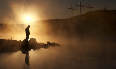 Three Crosses and Silhoutted Person in Prayer at Sunrise